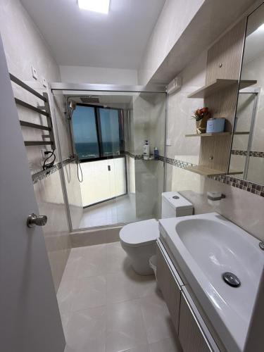 a white bathroom with a toilet and a sink at Oceanfront Playa Grande 10 min Airport Maiquetia Aeropuerto in Maiquetía