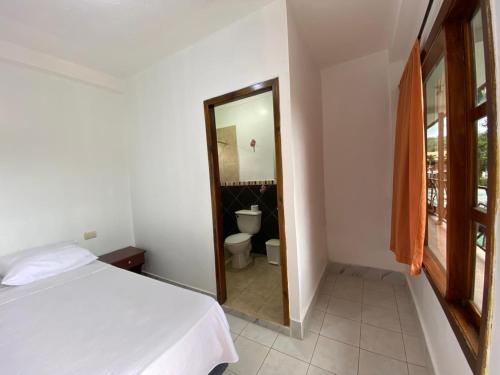 a bedroom with a bed and a bathroom with a toilet at Tierra y Mar in Montañita