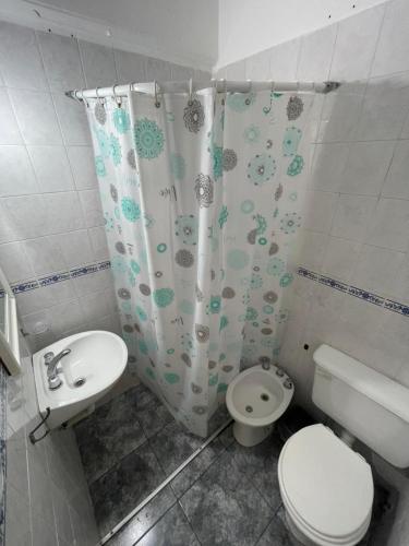 a bathroom with a toilet and a shower curtain at Los Manantiales in Villa Gesell