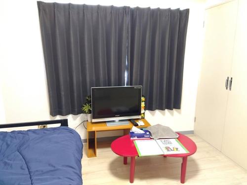 a room with a bed and a table with a television at SunandMoonホテル401 in Tokyo