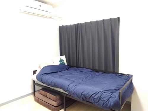 a bed with a blue comforter in a room at SunandMoonホテル401 in Tokyo