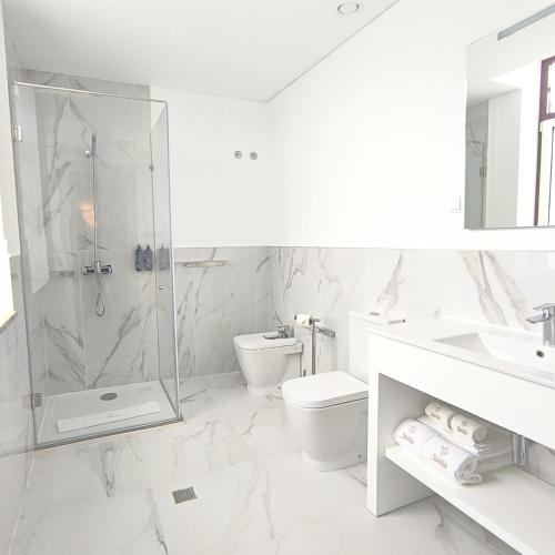 a white bathroom with a shower and a toilet at Stella Braga Aparthotel in Braga