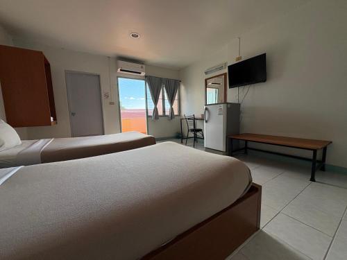 Una habitación de hotel con dos camas y un refrigerador. en Baansilp Hotel, en Chiang Rai