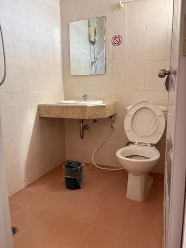 Un baño con inodoro, lavabo y espejo. en Baansilp Hotel, en Chiang Rai