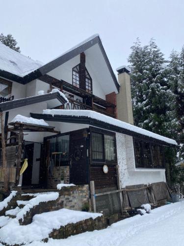 a house with snow on the front of it at Twin Peaks Lodge in Hakuba