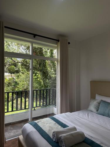 a bedroom with a bed and a large window at Nomentano Blue -Luxury Apartments- in Nuwara Eliya