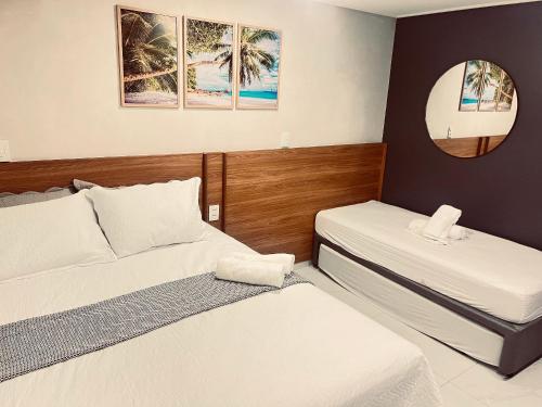 two beds in a hotel room with a mirror at Flat Elegante c/ Varanda e Vista Mar - Tambaú in Tambaú