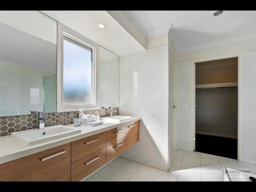 un bagno bianco con un lavandino e una finestra di Maison De Vacances a Banksia Beach