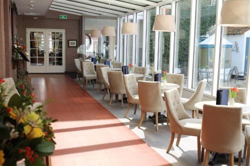 a dining room with tables and chairs and windows at Hotel Brull in Mechelen
