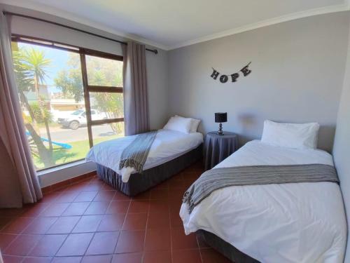two beds in a room with a window at Linaria Beach House in Britannia Bay