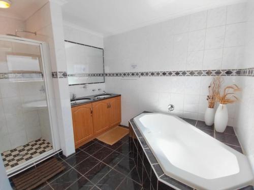 a bathroom with a tub and a sink and a bath tub at Linaria Beach House in Britannia Bay