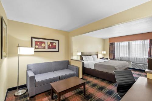 Quality Inn & Suites Des Moines Airport في دي موين: غرفة فندق مع سرير وكرسي
