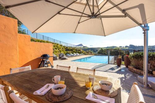 a wooden table with an umbrella next to a pool at The Villino at Cypress Ridge Estate - Stay Waiheke in Onetangi