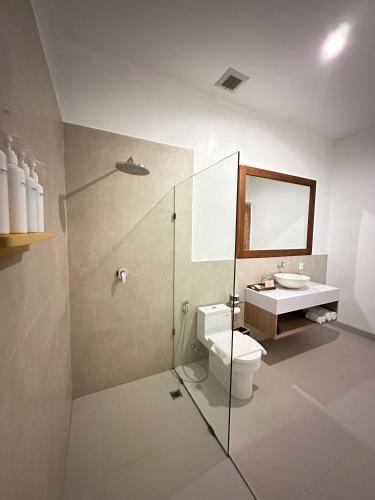a bathroom with a shower and a toilet and a sink at De Vindra Resort in Nusa Penida