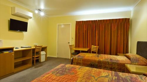 a hotel room with two beds and a desk at Motel Le Grande in Albany