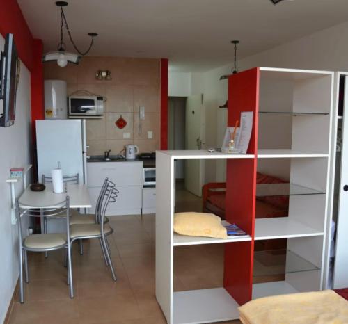 een keuken met een tafel en een rood-wit kastje bij Monoambiente en Miramar in Miramar
