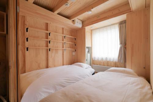two beds in a small room with a window at SMA MO inn Chitose in Chitose