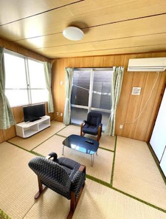 a living room with two chairs and a television at Miyagi Apartment Tomari in Naha