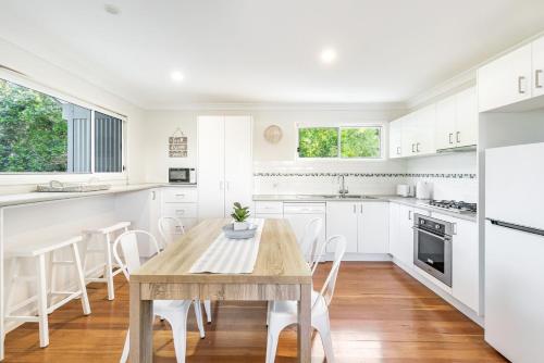 a white kitchen with a wooden table and chairs at Iluka Sea Spray in Iluka