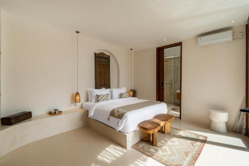 een witte slaapkamer met een bed en een badkamer bij Villa Le Bijou by BaliSuperHost in Mantaak