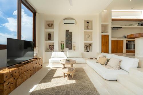 een woonkamer met een witte bank en een flatscreen-tv bij Villa Le Bijou by BaliSuperHost in Mantaak