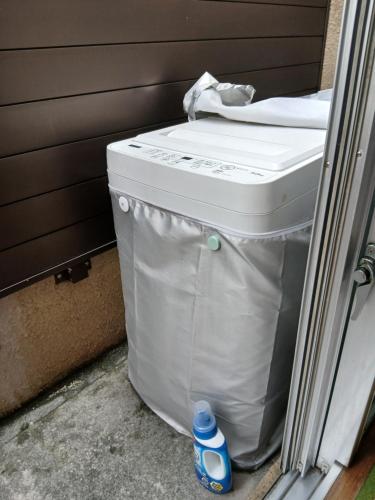 a large white trash can with a bottle next to it at Miyagi Apartment Tomari in Naha