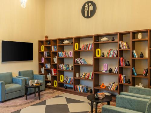 JāmbにあるThe Hosteller Bam Jaipur, Hawa Mahalの椅子2脚とテレビと本棚のある図書館