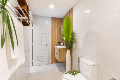 a bathroom with a toilet and a plant at Little Me Beachfront Villa in Nathon Bay