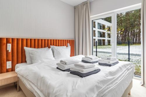 a bed with towels on top of it with a window at Hidden Coast - Premium Seaside Apartments with Pool, 2-Minute Walk to the Beach in Łukęcin