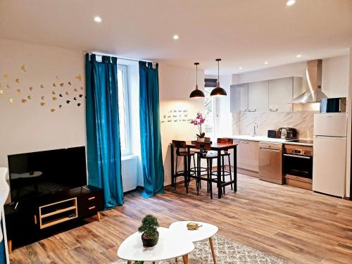 a kitchen and living room with blue curtains and a table at Le saphire St Affrique hyper centre ville in Saint-Affrique