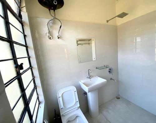 a bathroom with a sink and a toilet and a mirror at Mareenda's Haven in Shillong