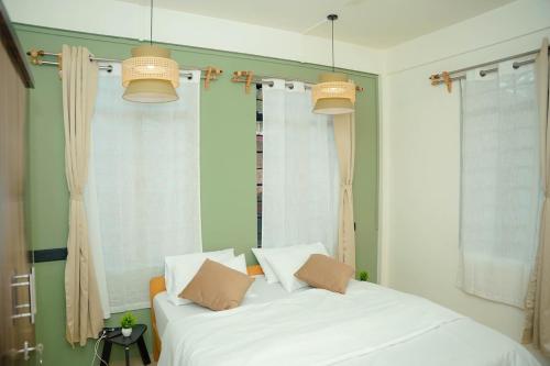 a bedroom with two white beds and two windows at Mareenda's Haven in Shillong
