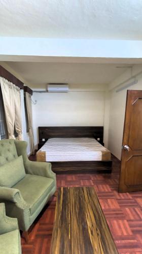 a bedroom with a bed and a couch and a chair at TUYU Chhye in Kathmandu