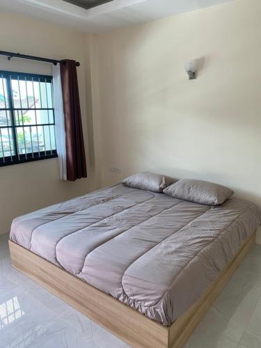 a large bed in a bedroom with a window at ZAMZAM House in Thalang