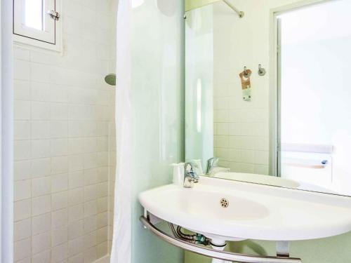 Un baño blanco con lavabo y espejo. en Ibis budget Périgueux, en Périgueux