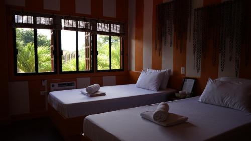 two beds in a room with two windows at Stefanie Grace Inn in Loboc