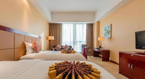 a hotel room with two beds and a flat screen tv at Qingdao Chengyang Detai Hotel in Qingdao