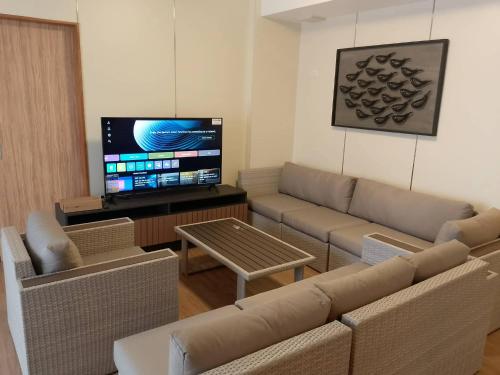 Luntian Luxury Condo in Tagaytay في Iruhin: غرفة معيشة مع أريكة وتلفزيون بشاشة مسطحة