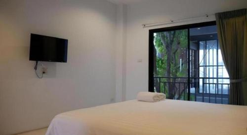 a bedroom with a bed with a television and a window at Sabai @ Chumphae Hotel in Chum Phae