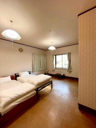 a bedroom with two beds and a window at 波浮とみや 全部屋個室 伊豆大島 in Oshima
