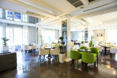 a restaurant with green chairs and tables and windows at Hotel Monarch in Elbasan
