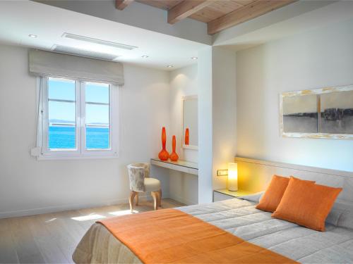 a bedroom with a bed with orange pillows and a window at Nissaki Beach Hotel in Naxos Chora