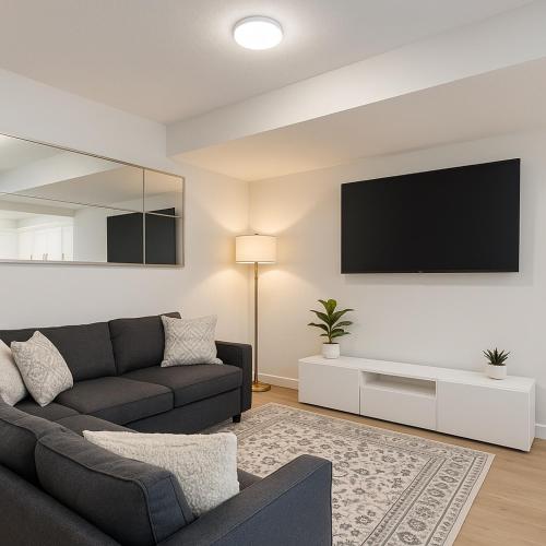 a living room with a couch and a flat screen tv at The Seton Nook - 1BR Suite Near Seton Health Campus, Cineplex and YMCA in Calgary
