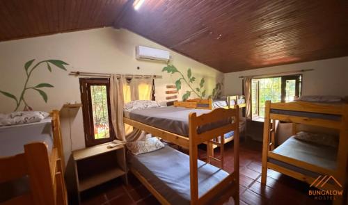a room with a bed and two bunk beds at Bungalow Hostel Iguazú in Puerto Iguazú
