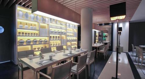 a restaurant with tables and chairs and a wall of dishes at Jinjiang Metropolo Classiq Shanghai Jing'an Temple in Shanghai