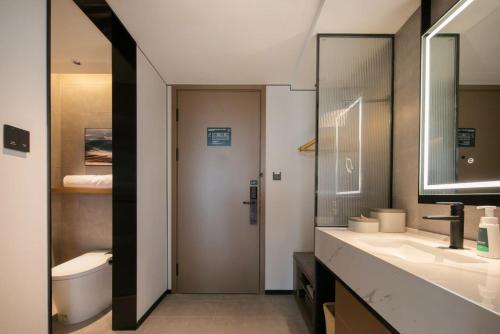 Atour Hotel Shanghai Baoshan Shangda Road في شانغهاي: حمام مغسلتين ومرحاض ومرآة