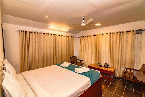 a bedroom with a bed and a table and a chair at Mia Riaan Lake View Resort in Ernakulam