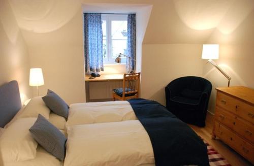 a bedroom with a bed and a chair and a window at Altstadthotel Bauern Bräu Schrobenhausen in Schrobenhausen