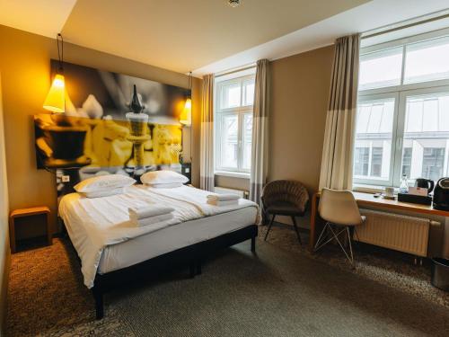 Un dormitorio con cama, escritorio y ventanas en Ibis Riga Centre, en Riga