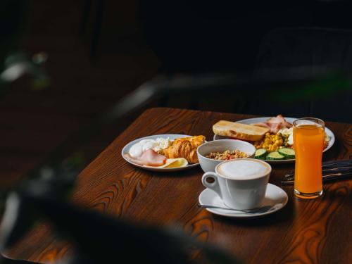 een tafel met borden en een kop sinaasappelsap bij Ibis Riga Centre in Rīga